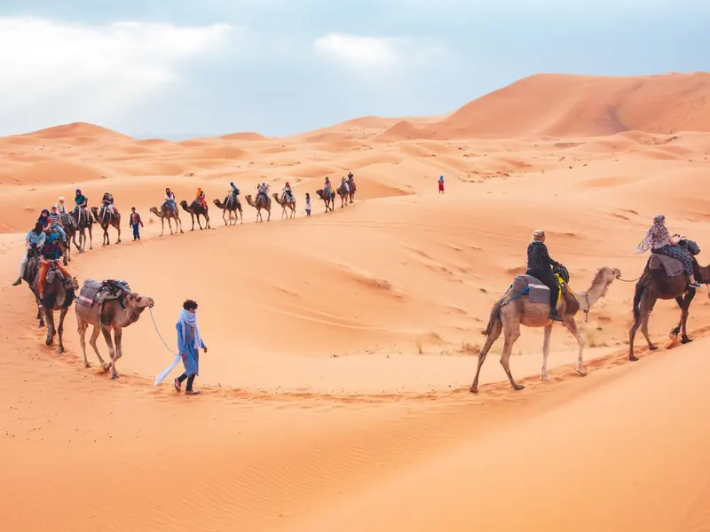 Viajeros montando en dromedario por las dunas de Erg Chebbi en Merzouga