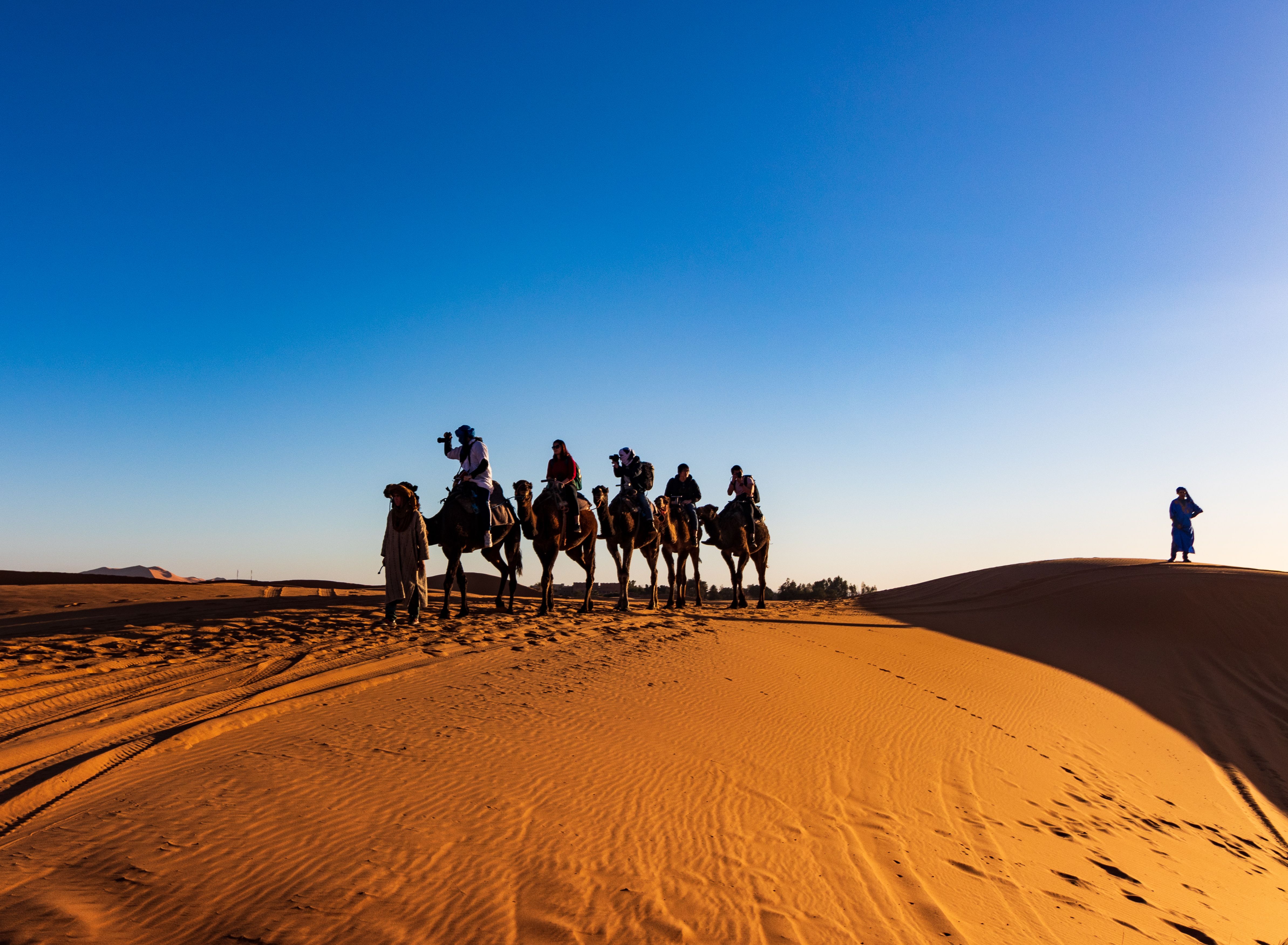 Grupo de viajeros montando en dromedario por el desierto
